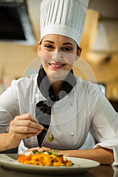 Happy head chef garnishing pasta dish with olive