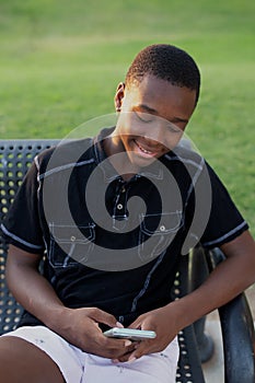 Black Teen Boy Using His Cell Phone Outside