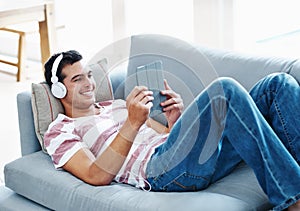 Happy, headphones and man with tablet on sofa for online streaming, movie and watching video. Relax, smile and male