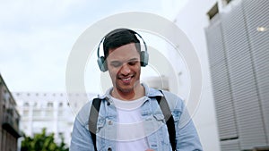 Happy, headphones and phone of a man in the city walking, listening and streaming music on the internet outside. Male in
