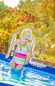 Happy healthy child in swimwear standing in swimming pool