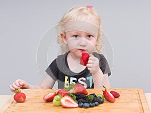 Happy kid  eating fresh strawberries