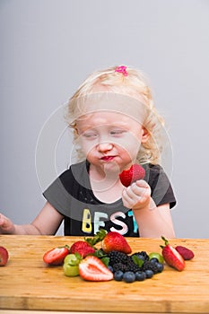 Happy kid  eating fresh strawberries