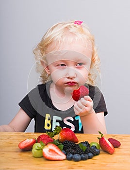 Happy kid  eating fresh strawberries