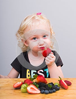 Happy kid  eating fresh strawberries