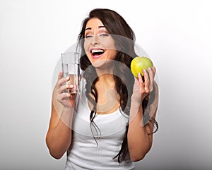 Happy healthy laughing woman holding apple and clear water in two hand and looking with toothy smiling.
