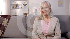 Happy healthy old woman smiling camera sitting sofa, retirement wellness, beauty