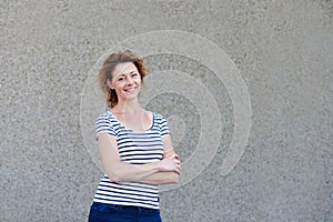 Happy healthy older woman standing by wall outside