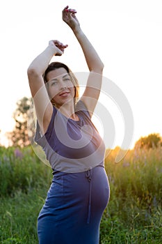 Happy healthy pregnancy and maternity. Portrait of pregnant young caucasian woman wearing long blue dress posing in park