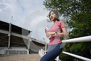 Happy healthy woman drinking water from bottle after workout exercise. Sports, nutrition bottle, and female athletes drink liquid