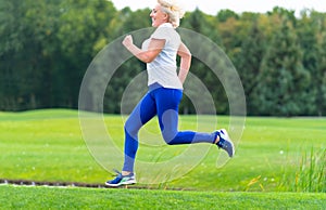 Happy healthy woman running through a park