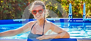 Happy healthy woman in swimming pool in sunglasses