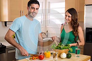 Happy healthy young vegan couple cooking vegetables at home