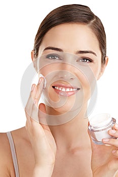 Happy with her new skincare product. Cropped portrait of a beautiful young woman applying moisturizer against a white