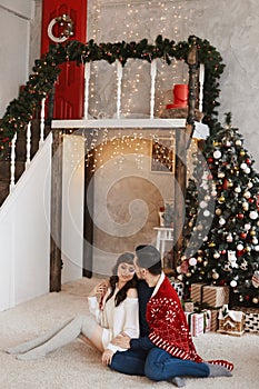 Happy heterosexual couple hugs together in a living room decorated for Christmas