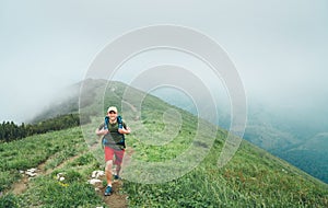Happy hiker man walking by the cloudy and foggy weather mountain range path with backpack. Active sport backpacking healthy