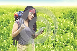 Happy hiker with smartphone in the flower field