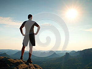 Happy hiker is standing on sharp cliff in rock empires park and watching over the misty and foggy morning valley to Sun.
