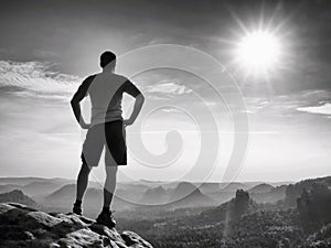 Happy hiker is standing on sharp cliff in rock empires park and watching over the misty and foggy morning valley to Sun.