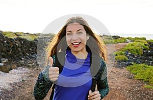 Happy hiking woman giving thumbs up smiling. Young hiker woman smiling joyful at camera outdoor on hike trip.