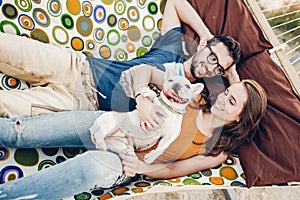 Happy hipster couple with bulldog relaxing in hammock on the beach in sunset light, summer vacation. stylish family with dog