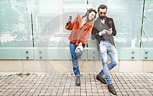 Happy hipster couple having fun with mobile smart phone at outdoors location - Friendship concept with best friends connecting