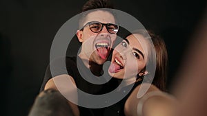 Happy hipster couple taking a selfie on black.