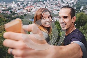 Happy hipster couple taking selfie on phone on background of beautiful view on old town building in Europe. Tourist couple smiling