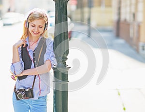 Happy hipster girl listening music on city street