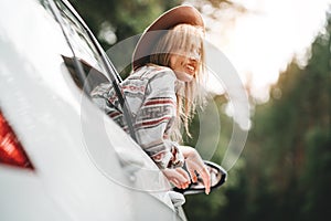 Happy hipster girl traveling adventure vacations. Boho woman sitting in car looking from window on view in country road