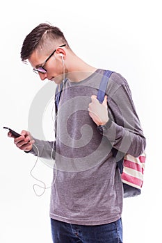 Happy hipster guy with backpack and using a smart phone to listen music with headphones