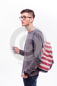 Happy hipster guy in glasses with backpack using a smart phone to listen music