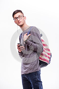 Happy hipster guy in glasses with backpack using a smart phone to listen music