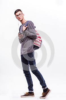 Happy hipster guy in glasses with backpack using a smart phone to listen music