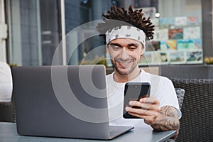 Happy hipster guy holding smartphone, excited with good news getting in sms message, receive payment, winning online contest on