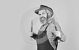 happy hipster hold cooking utensils for barbecue. bearded man chef. Tools for roasting meat outdoors. Picnic and