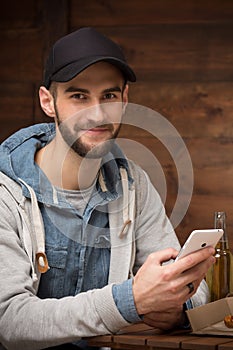 Happy hipster man sitting in the cafe with mobile phone