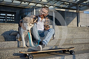 Happy hipster man skateboarder resting and sitting with loving dog