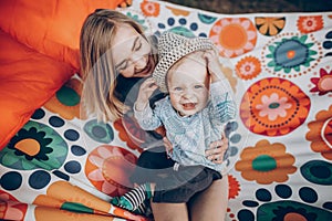 Happy hipster mother playing with her cute little son on hammock in summer sunny park. stylish mom with kid relaxing in forest and