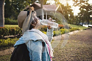 Happy hipster old women drinking water of bottle during backpack