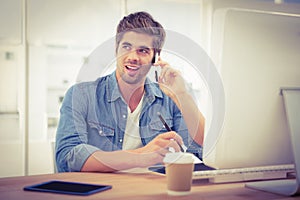 Happy hipster using mobile phone while sitting at desk