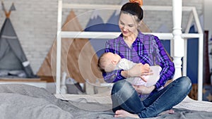 Happy hipster young mother enjoying motherhood lulling little cute baby full shot