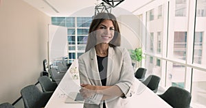 Happy Hispanic businesswoman in elegant jacket posing in modern boardroom