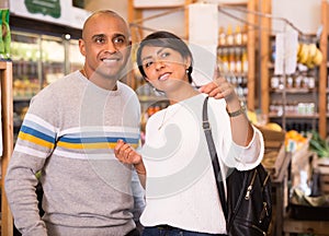 Happy hispanic couple choosing foods in grocery shop