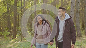 Happy hispanic couple in love walking in park to sunshine smiling young girl and guy walks holding hands chatting