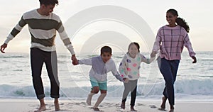 Happy hispanic family running on beach and having fun at sunset