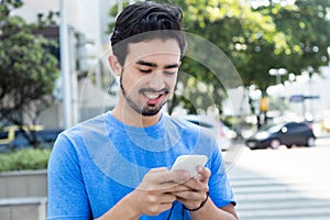 Happy hispanic guy surfing the web with phone