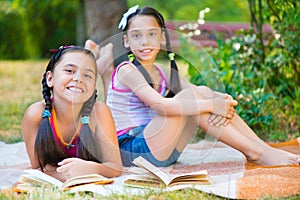 Happy hispanic sisters reading in the park