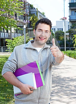 Happy hispanic student at campus showing thumb up