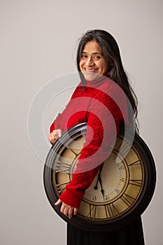 Happy Hispanic Woman Holds Clock Under Arm And Looks Toward Camera